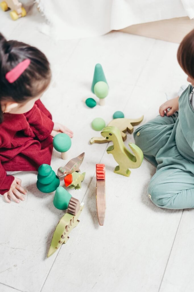 Crianças a brincar no chão com brinquedos de madeira
